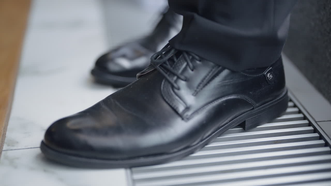 검은색 슈트 신발을 입은 남자가 난방 통로를 고 있다