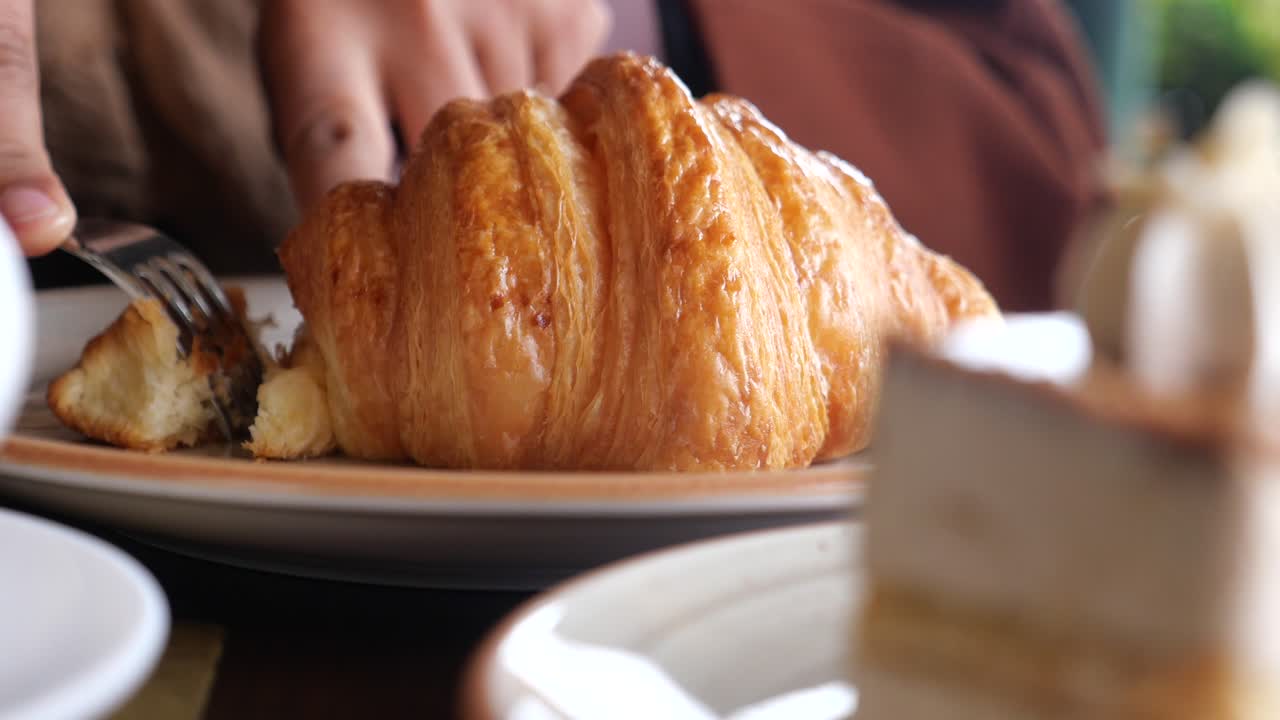 Primo piano della mano di una donna che tiene un croissant