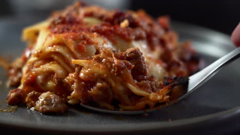 close up of a fork cutting a beautiful piece of a sumptuous traditional italian lasagna