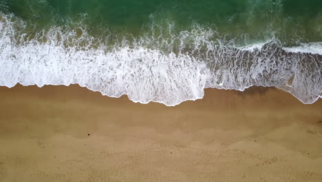 Vista-Aérea-De-Arriba-Hacia-Abajo-De-Las-Olas-Rompiendo-En-La-Costa,-Perspectiva-Calmante,-Drone