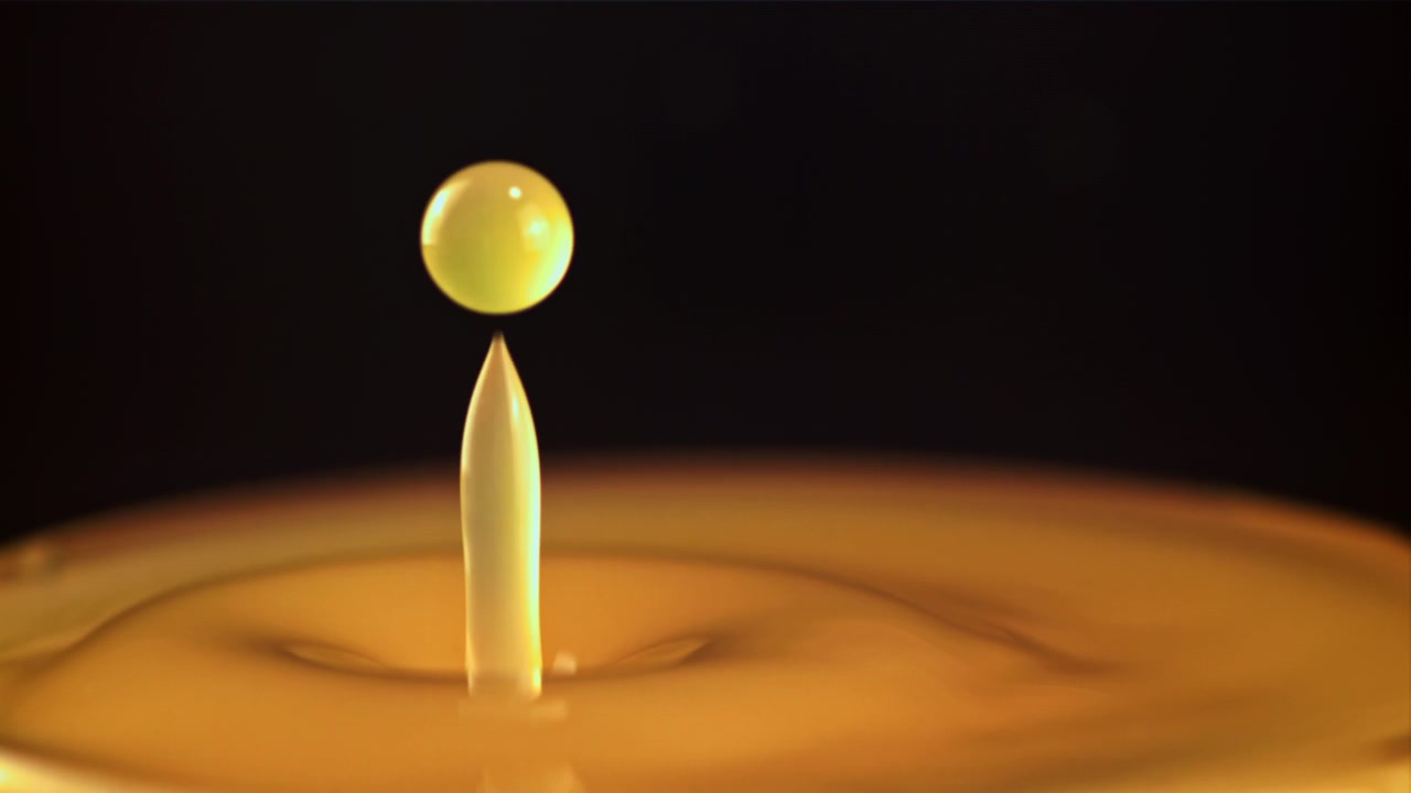 Slow Motion Golden Liquid Drop Splashing and Forming a Crown