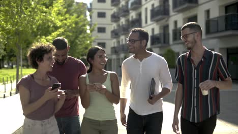 Mujer-Joven-Alegre-Mostrando-Teléfono-Inteligente-A-Sus-Amigos.