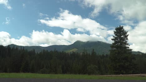 static view over beautiful mountains in forest wilderness in distance with slow moving clouds