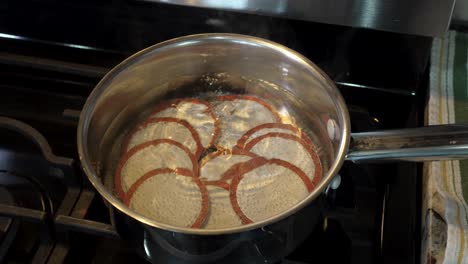 Canning-jar-lids-boiling-in-the-water-before-being-sealed-on-the-jars---slow-motion