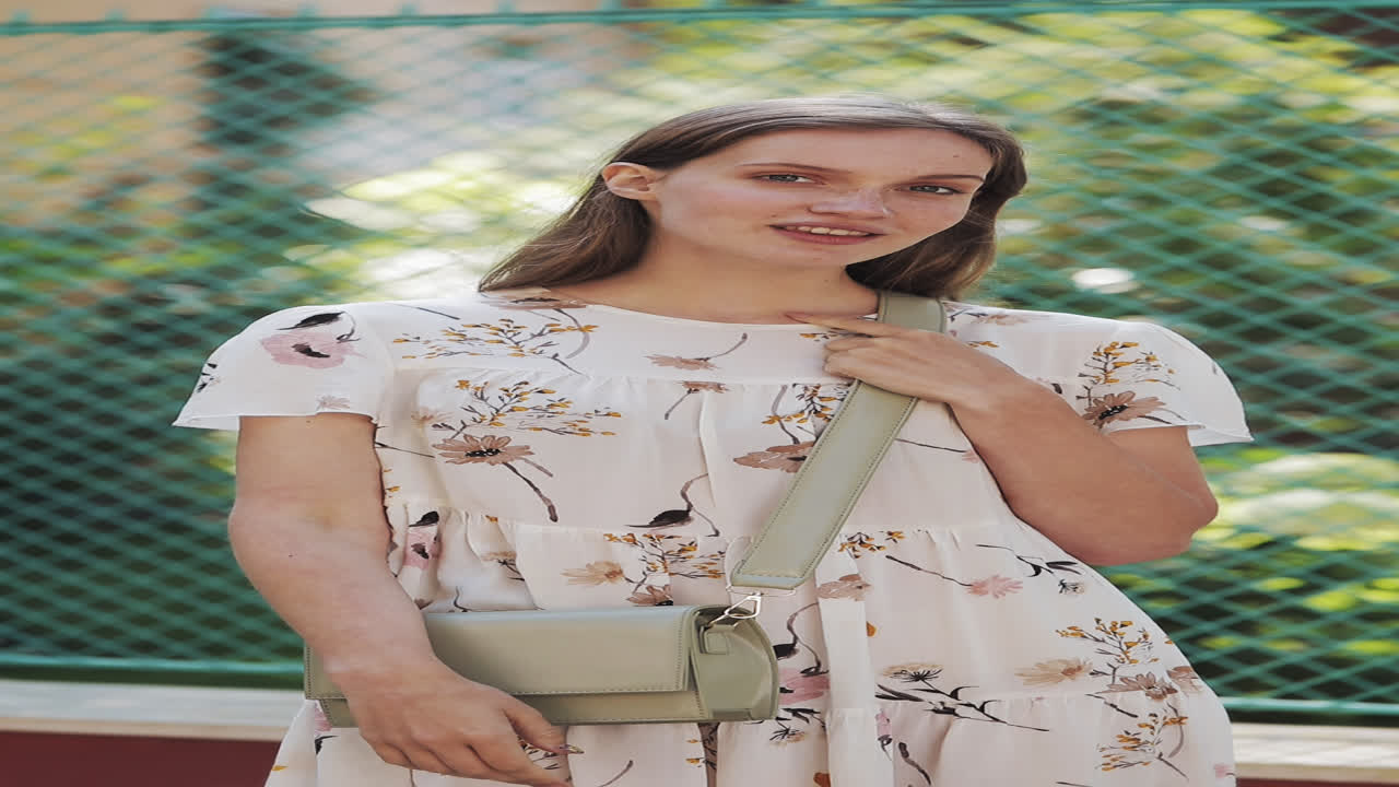 Giovane donna in abito floreale in posa e sorridente all'aperto
