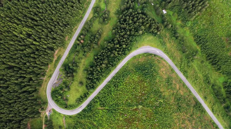 Vista aerea dall'alto con drone di auto che percorrono una bellissima strada a forma di S nelle montagne del Parco Nazionale dei Bassi Tatra in Slovacchia.