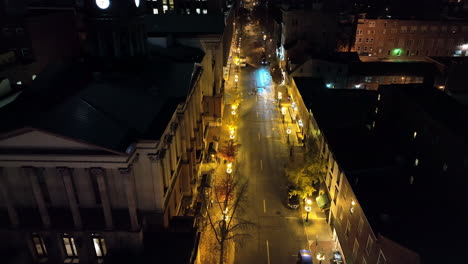aerial of traffic driving in urban downtown city at night. glow of lights. establishing shot. government courthouse building.