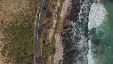 Aerial-drone-view-of-cars-driving-next-to-ocean-coastline