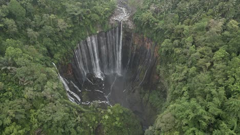 aerial tilts down to huge waterfall grotto on java, tumpak sewu