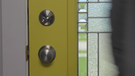 Formal-man-in-shirt-entering-the-interior-of-a-house-through-a-yellow-door-with-glass