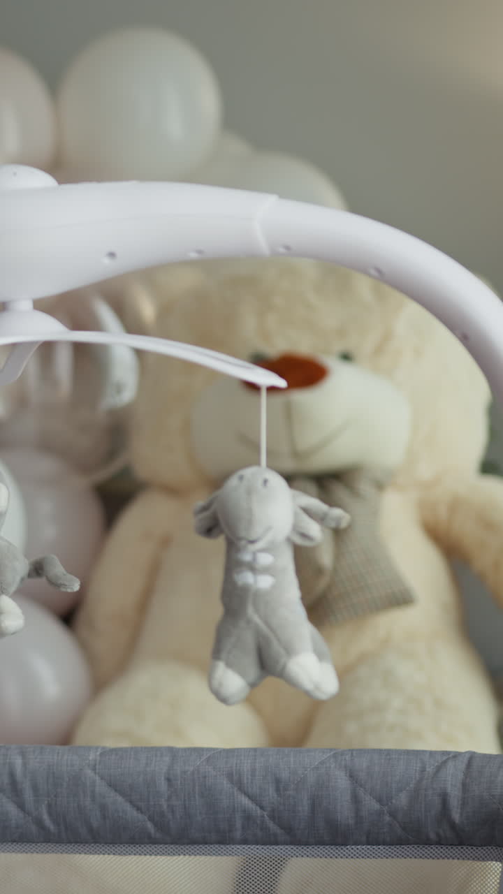 Primo piano di una giostrina per culla con giocattoli di peluche, tra cui un orsetto e una pecora, progettata per.