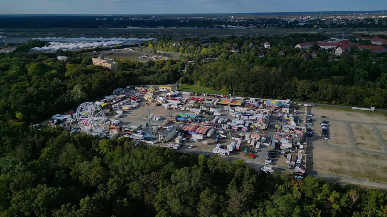 Berlin funfair showing a Ferris wheel, amusement rides, and various stalls from an aerial perspective. Fabulous aerial view flight panorama orbit drone