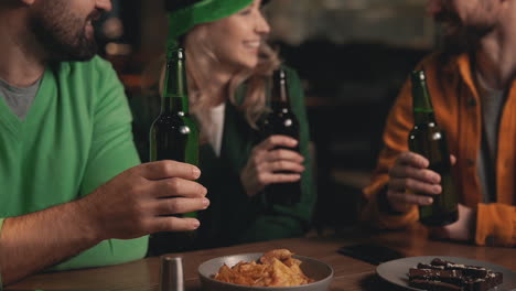 young men and beautiful woman toasting with beer bottles