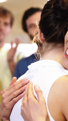 two womens hugging each other while colleagues clapping in background