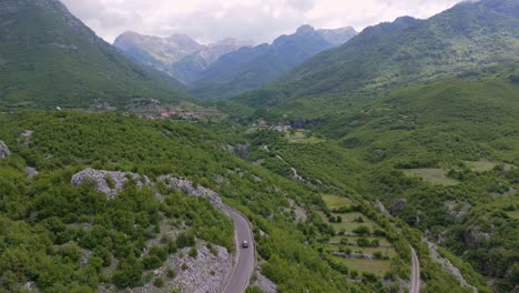 a car drives along the winding roads of the malësia e madhe mountain range in northern albania, known for its stunning views