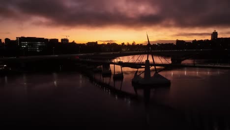 aerial shot of south bank's goodwill bridge at sunrise, with bridge silhouetted over orange sky