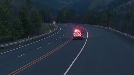 Drohnenaufnahme-Eines-Feuerwehrfahrzeugs,-Das-Nachts-Auf-Der-Autobahn-Neben-Dem-Fluss-Fährt,-Aus-Nächster-Nähe