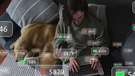 iconos digitales en burbujas de habla contra mujer caucásica usando computadora portátil mientras el perro duerme en el sofá
