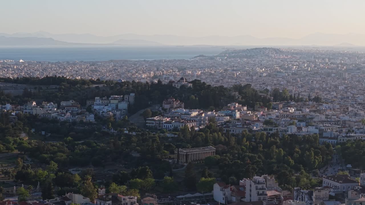 Aerial drone footage captures the cityscape of Athens with the ancient Temple of Hephaestus in the foreground and the historic National Observatory in the background