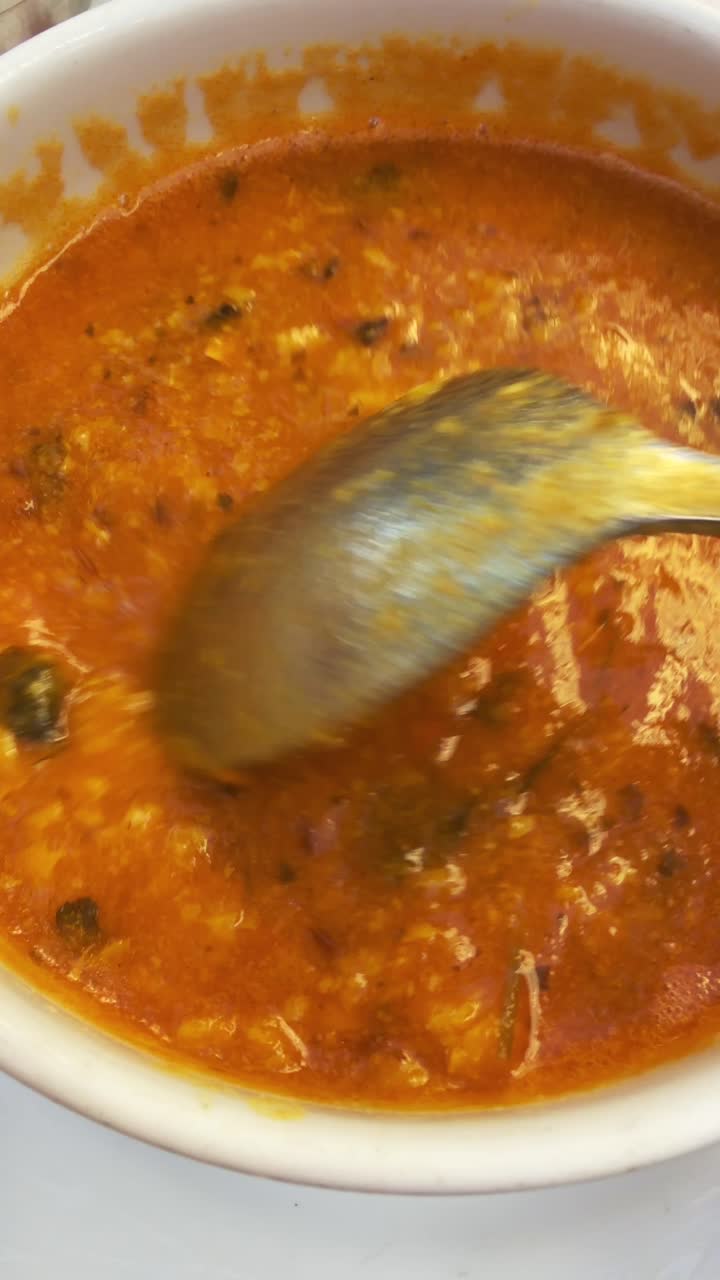 Soup in a bowl being stirred with a ladle