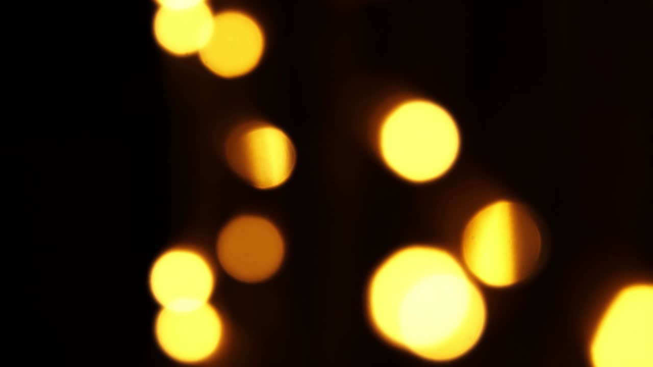 fondo bokeh abstracto en movimiento. brillantes, partículas doradas borrosas, luces. bokeh brillante de guirnaldas en fondo oscuro. telón de fondo festivo de año nuevo o navidad