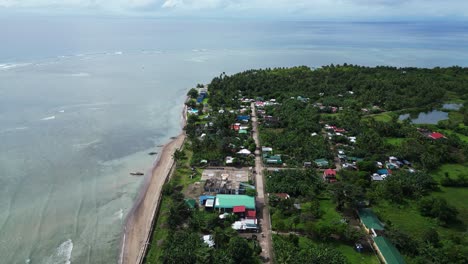 aerial drone view of rural, coastal fishing village on tropical island with lush jungles and idyllic sea coast