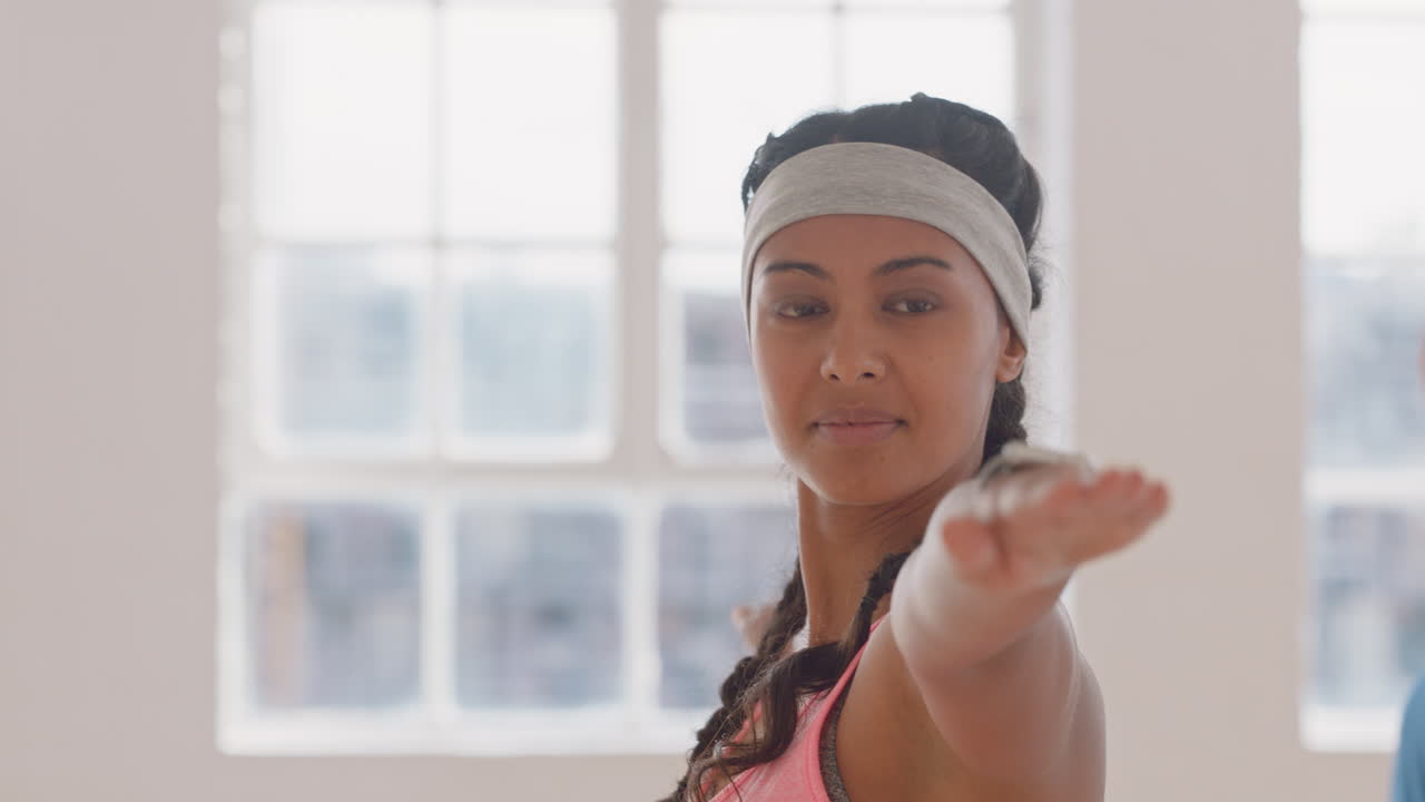 portrait beautiful young mixed race woman exercising in yoga class practicing warrior pose enjoying group physical fitness workout