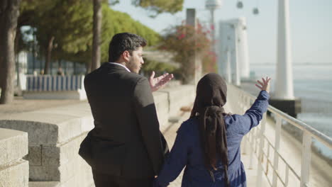 Back-view-of-Arabic-couple-walking-along-quayside