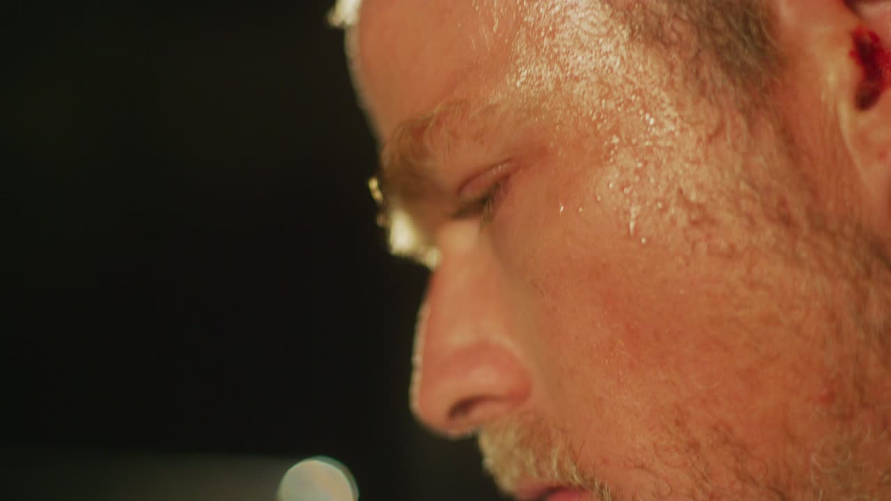 을 흘리는 남자가 빛에 눈이 멀었을 때 주위를 둘러보고 있습니다.