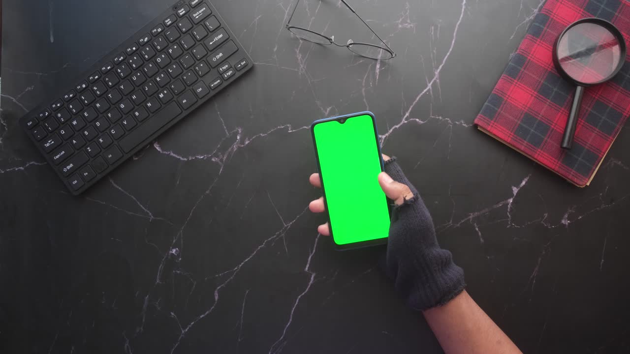 persona usando un teléfono inteligente con una pantalla verde en un escritorio de mármol oscuro