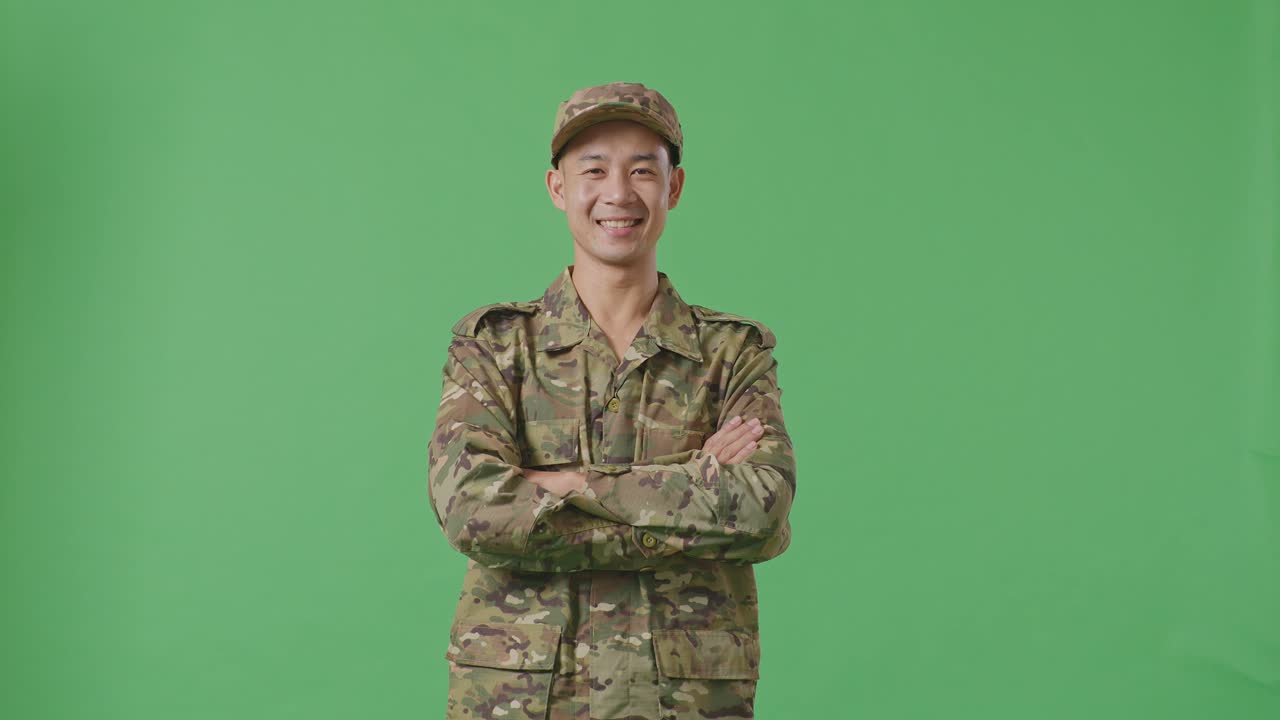 Asian Man Soldier Smiling And Crossing His Arms While Standing In The Green Screen Background Studio