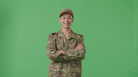 asian man soldier smiling and crossing his arms while standing in the green screen background studio