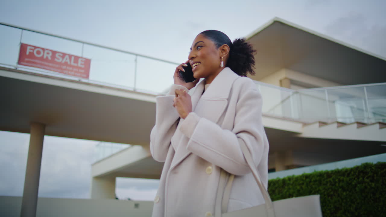 Realtor talking phone client at house for sale. Happy african american discuss