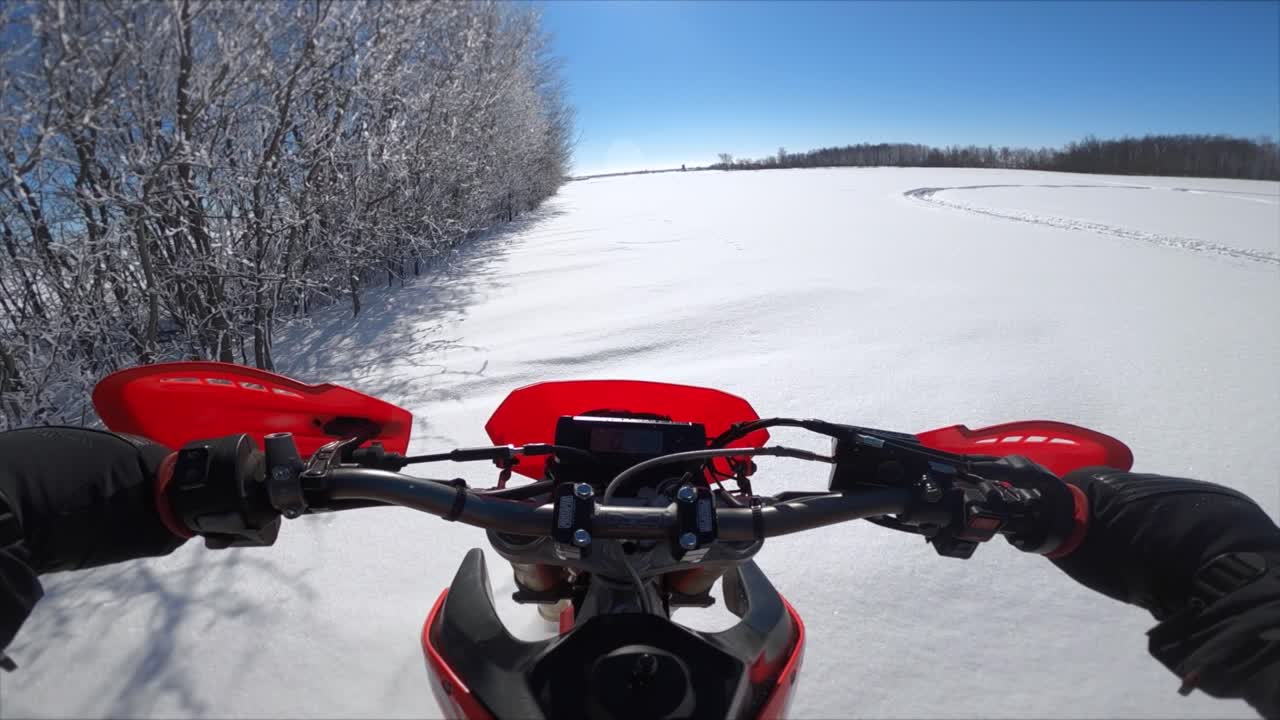 들판의 눈 덮인 나무를 따라 신선한 가루를 타고 있는 snowbike pov