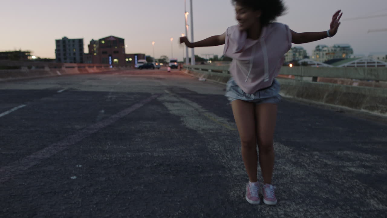 mujer bailarina de calle de raza mixta mujer con afro funky realizando movimientos de hip hop de estilo libre disfrutando de la expresión de danza moderna en la ciudad al atardecer