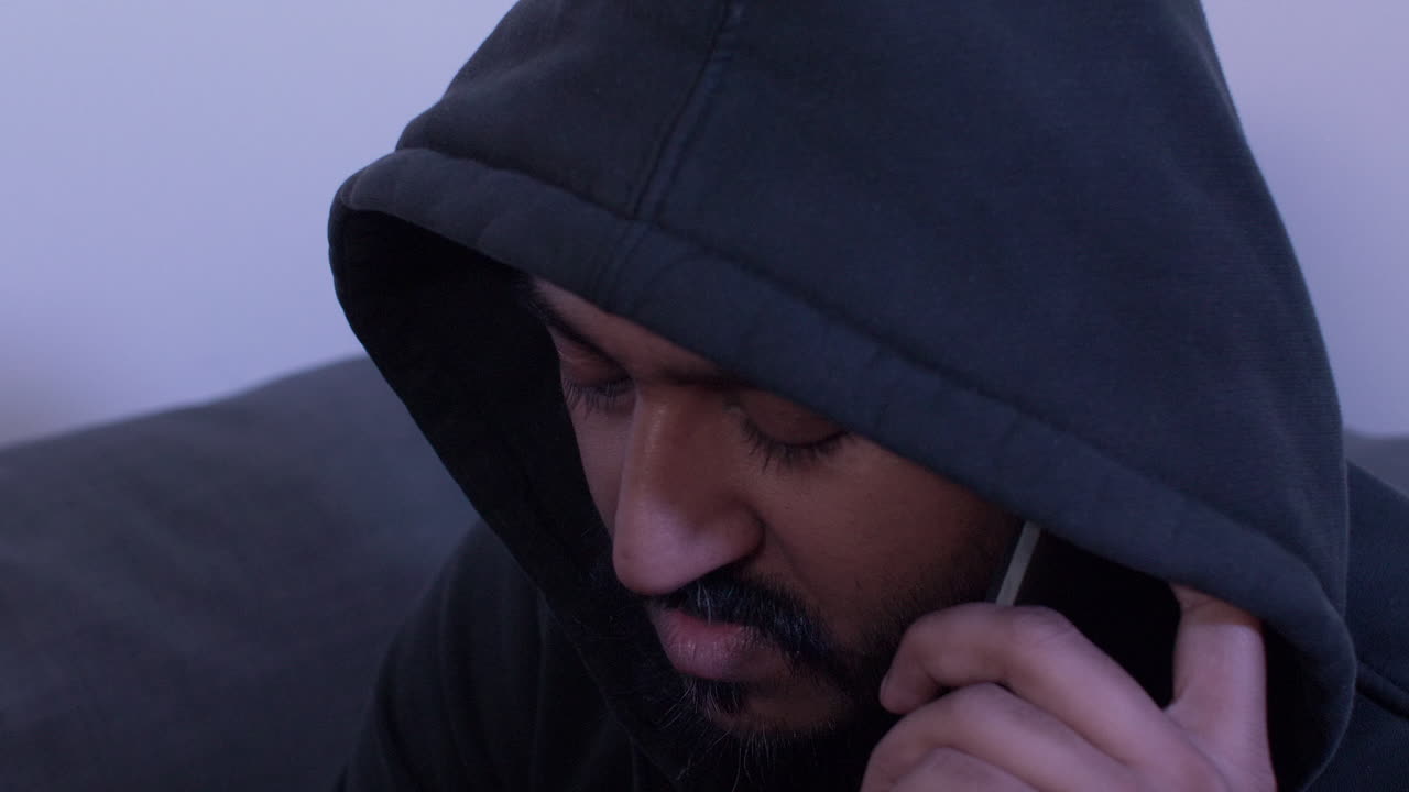 hombre con capucha hablando por teléfono móvil