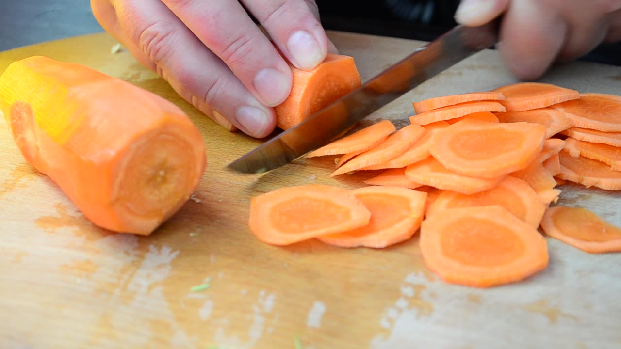 Taglio di carote. Il cuoco taglia le carote.