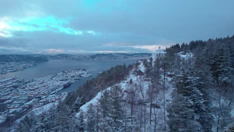 aerial view of fløyen, bergen, flying above norwegian bryggen covered in snow during wintertime