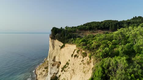 Sonnendurchflutete-Klippen-Der-Insel-Korfu-Mit-Blick-Auf-Das-Ionische-Meer,-üppiges-Grün-Umhüllt-Die-Landschaft,-Luftaufnahme