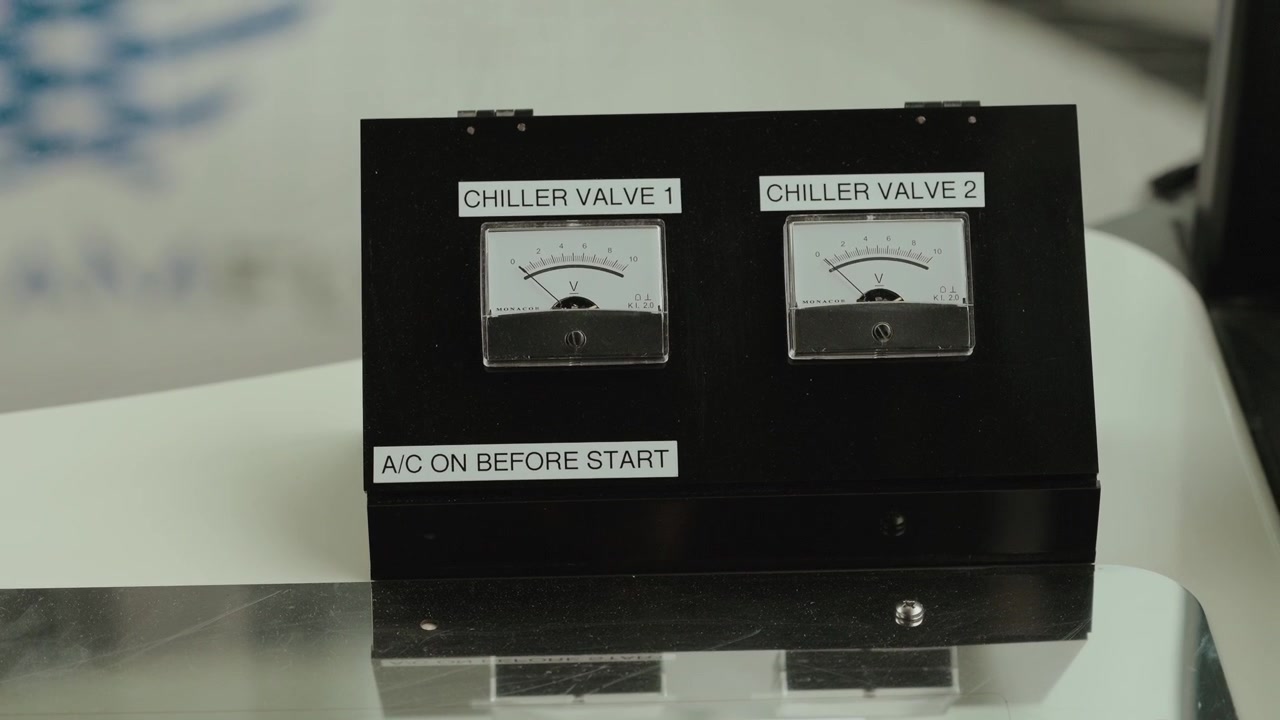 Primo piano di indicatori analogici etichettati "valvole del refrigeratore" su un sistema di controllo industriale.