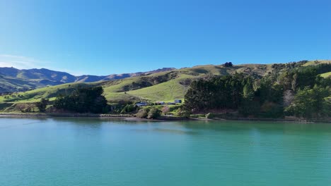 aerial footage of akaroa's serene lake and rolling hills under clear blue skies