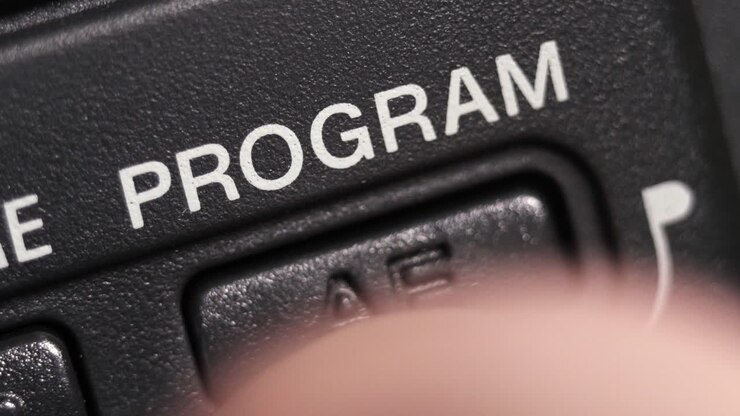 Diagonal macro of Program AE on dark grey plastic with white lettering