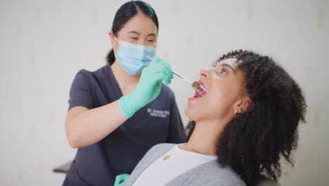 dentist with face mask checking teeth of a female