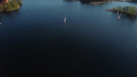 yacht sailing alongside trakai island castle on lake galve, lithuania