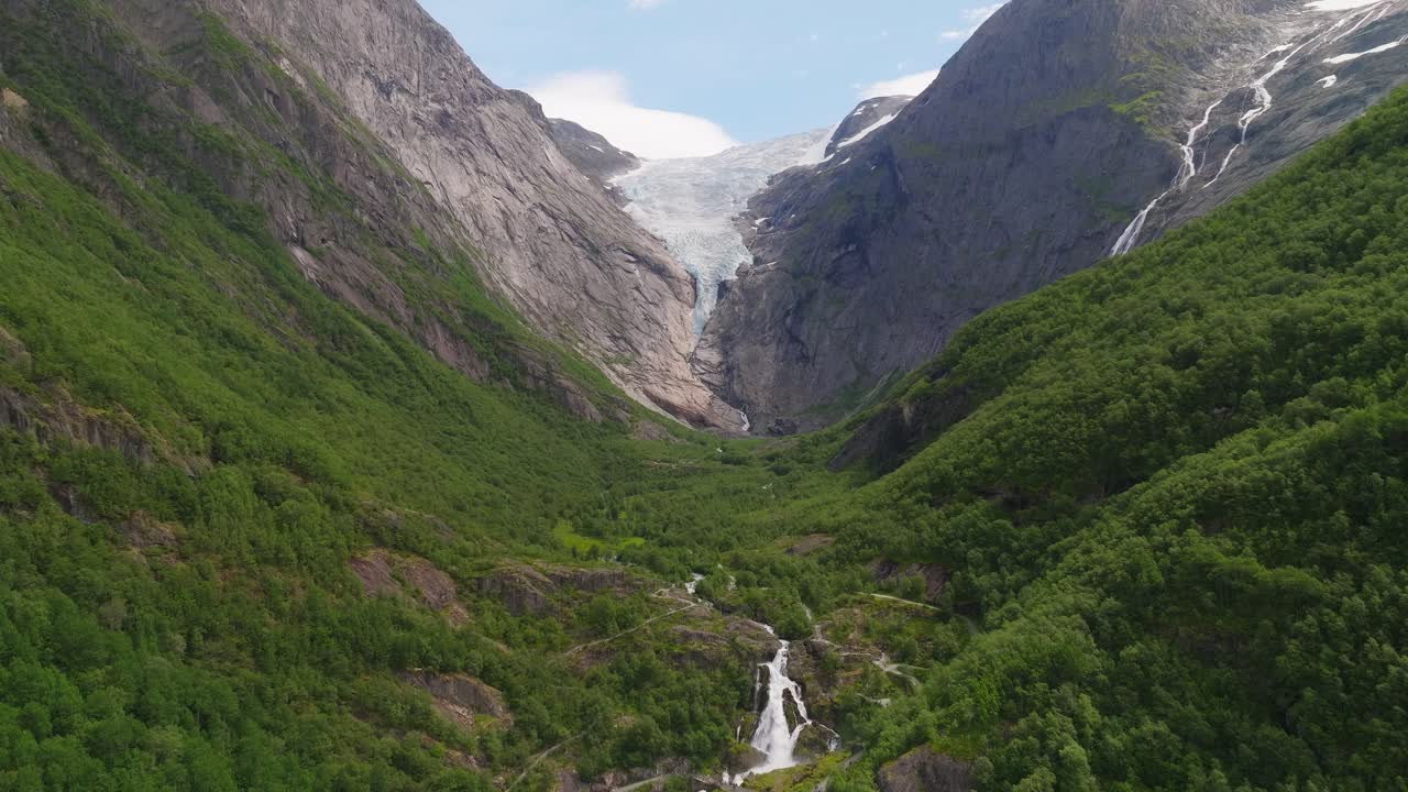 Majestátní ledovec Briksdalsbreen v Norsku s bujným zeleným údolím a kaskádovitými vodopády.