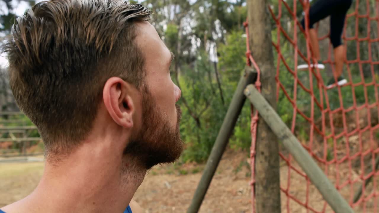 retrato de un entrenador masculino de pie en el parque durante una carrera de obstáculos