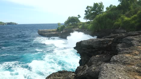 Slow-motion-wide-shot-of-waves-crashing-against-a-cliff-in-Nusa-Lembongan,-Indonesia