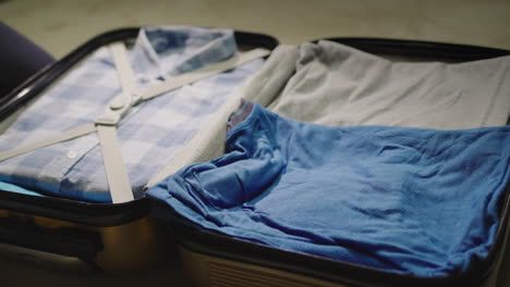 the woman puts clothes & protective masks in a suitcase