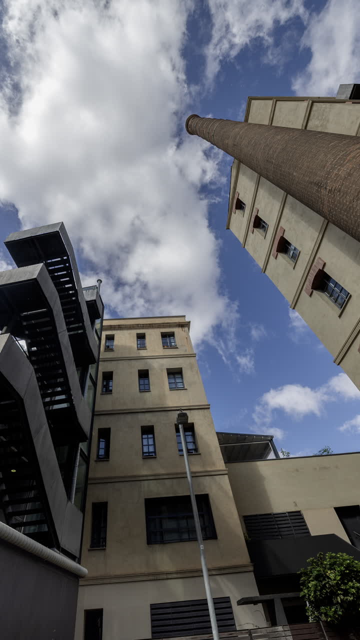 Old factory chimney and apartment buildings in barcelona in vertical