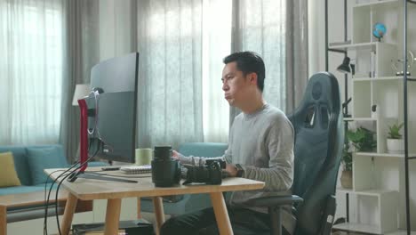 un camarógrafo asiático con una camiseta de mangas largas y pantalones negros está cansado mientras usa una computadora de escritorio para trabajar en casa.